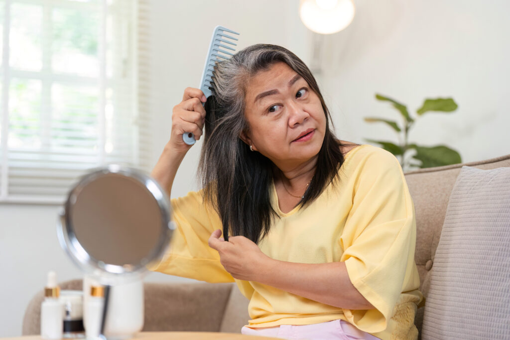 Hair Care and Beauty. A woman combing her hair while focusing on her appearance.